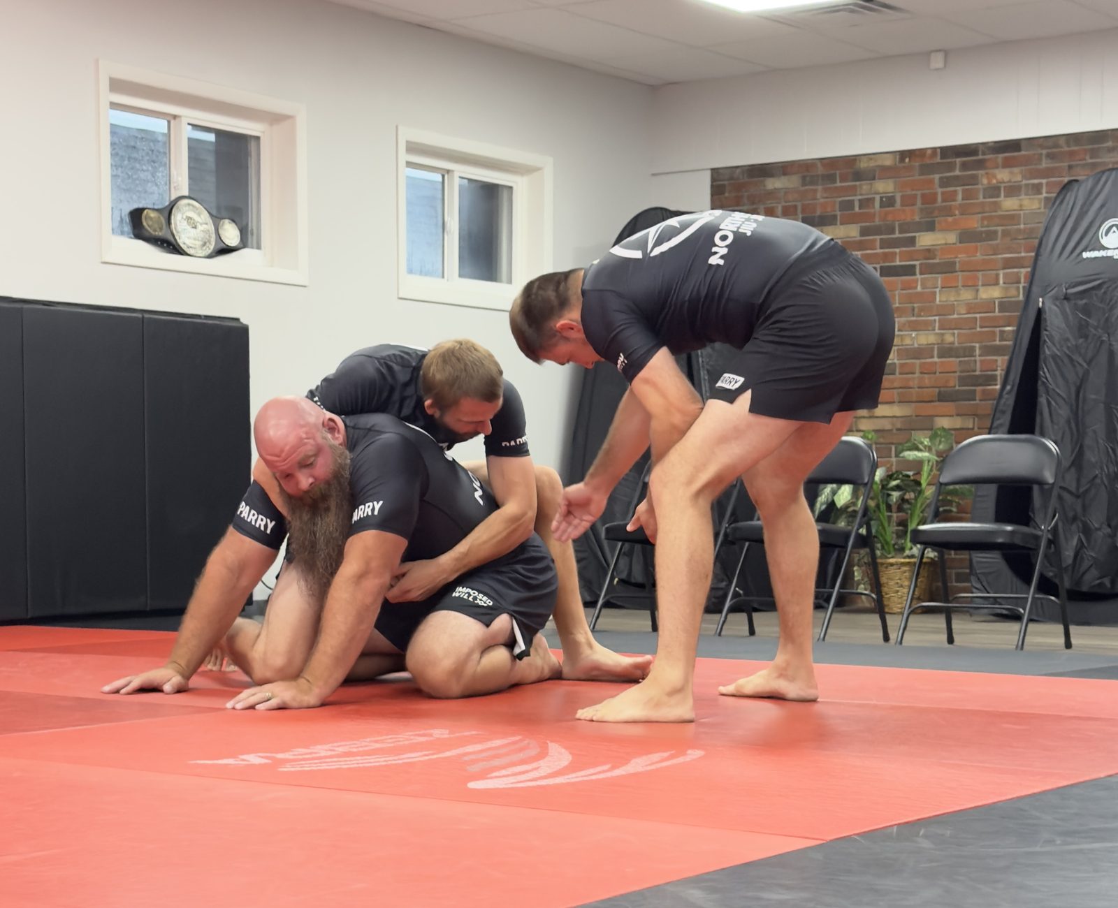 Head instructor Nicholas Craton coaching two students through a position on the mat during a no-gi class at Northstar Jiu Jitsu in Eau Claire