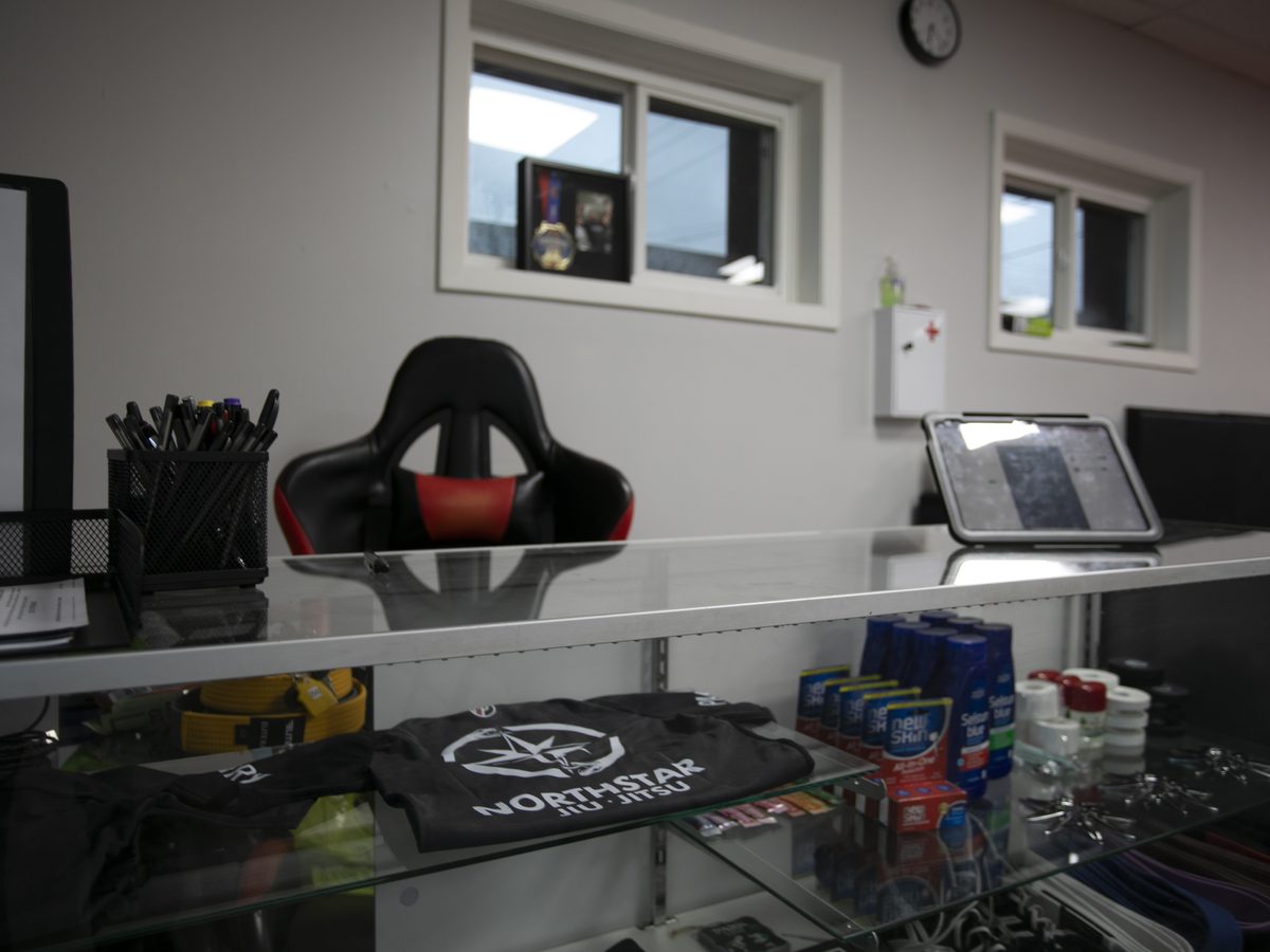 The front desk at Northstar Jiu Jitsu in Eau Claire, with a Northstar shirt and training supplies in the glass display case