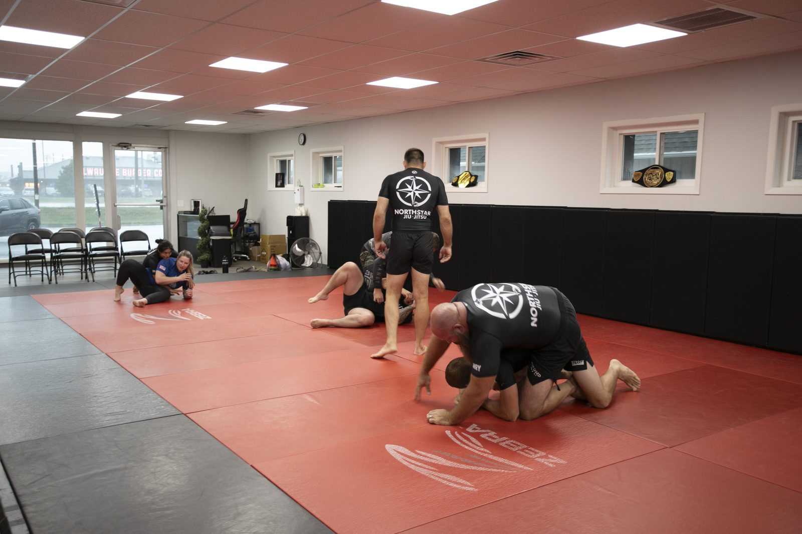 Several pairs of grapplers training across the full mat during an open mat session at Northstar Jiu Jitsu in Eau Claire